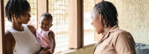 Mum and baby girl smile and interact with Ghana Health Service Community Health Worker