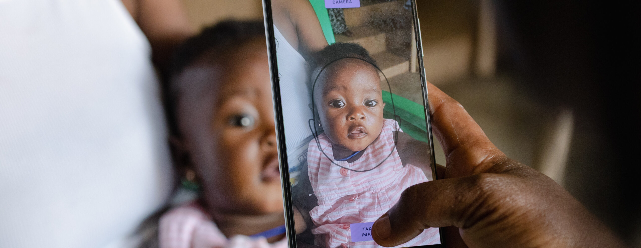 Baby girl having her facial biometrics captured on a mobile phone via Simprints ID app