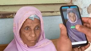 Lady in pink headscarf has her face biometrics recorded on a mobile phone