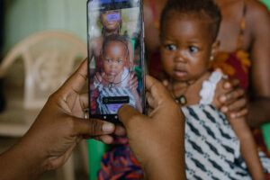 Young child at a Ghana health clinic having face scanned with SID app